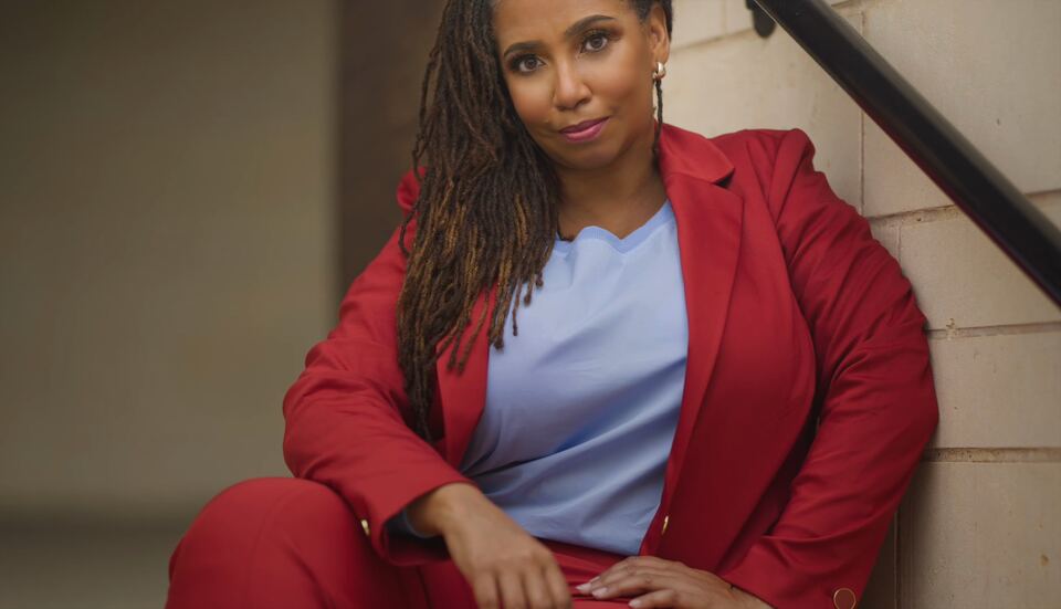 Hedreich Nichols seated on a stairway in a red blazer